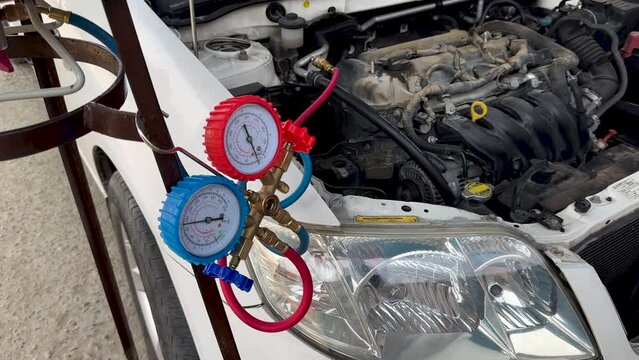 Mechanic Checking Automotive AC Pressure Gauges with Tools