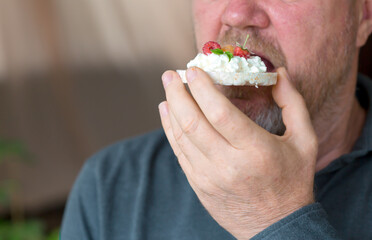 A man eats a sandwich with cottage cheese.