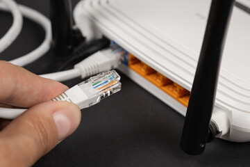 Man plugging internet cable into wi-fi router