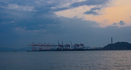 Serene view of a port with cranes under a cloudy evening sky by the water