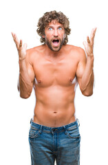 Fototapeta premium Handsome hispanic model man sexy and shirtless over isolated background celebrating crazy and amazed for success with arms raised and open eyes screaming excited. Winner concept