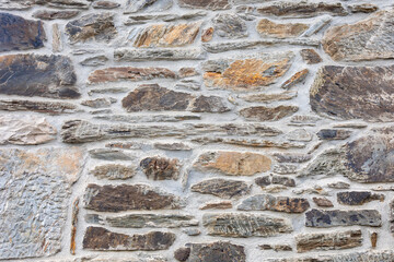 Close-up view of an old stone wall featuring various textured rocks meticulously placed with visible mortar, evoking a sense of antiquity and craftsmanship. 