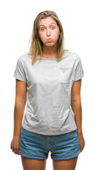 Obraz premium Young beautiful woman over isolated background puffing cheeks with funny face. Mouth inflated with air, crazy expression.