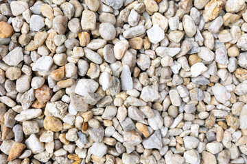 An assortment of diverse, small to medium-sized rocks and pebbles in a range of colors including grays, whites, and beiges, creating a natural and textured surface pattern.