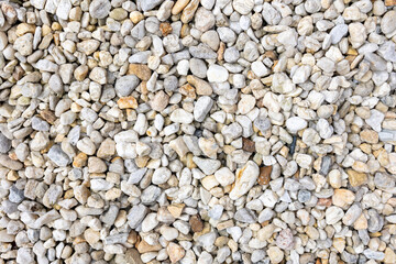 An assortment of diverse, small to medium-sized rocks and pebbles in a range of colors including grays, whites, and beiges, creating a natural and textured surface pattern.