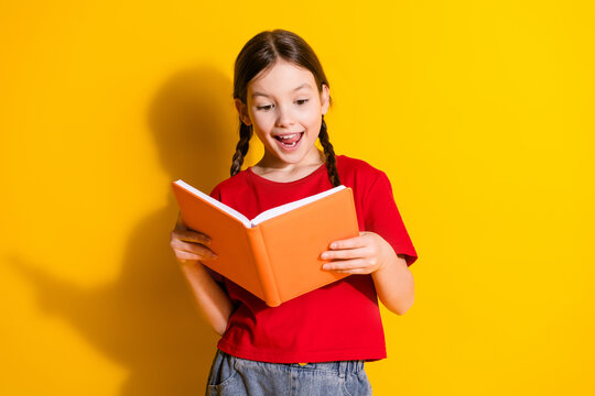 Portrait of cute little girl read book wear t-shirt isolated on yellow color background