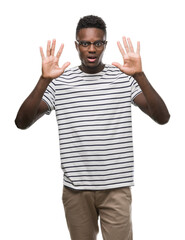 Young african american man wearing glasses and navy t-shirt showing and pointing up with fingers number ten while smiling confident and happy.