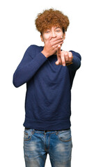 Young handsome man with afro hair Laughing of you, pointing to the camera with finger hand over mouth, shame expression