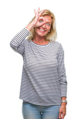 Middle age blonde woman over isolated background doing ok gesture with hand smiling, eye looking through fingers with happy face.