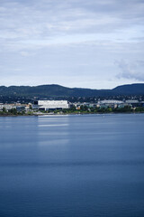 Fototapeta premium A distant view of Fornebu, a peninsula in Norway on the Oslofjord. The shot captures a cityscape with residential area including large, modern office buildings and a Stadium.