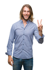 Young handsome man with long hair over isolated background smiling with happy face winking at the...