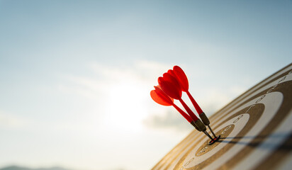 Close up shot red darts arrows in the target center on dark blue sky background. Business target or...