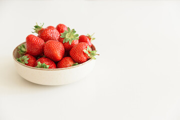 Fresh strawberries into bowls on white table. Summer food concept. Soft focus. Copy space