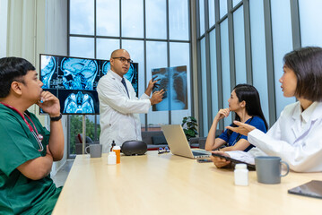 Group of professional doctors engaged in a discussion or meeting in a medical office. A large monitor displaying multiple MRI brain scans, to revolve around patient diagnosis and treatment planning.