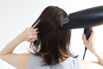 Fototapeta premium ドライヤーで髪の毛を乾かす女性