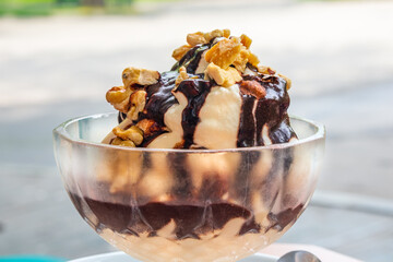 Ice cream with chocolate topping and walnuts in a glass outdoors. Dessert close-up. Soft Selective Focus