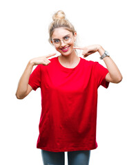 Young beautiful blonde woman wearing red t-shirt and glasses over isolated background smiling confident showing and pointing with fingers teeth and mouth. Health concept.