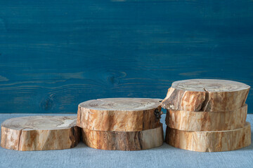 Fototapeta premium Empty podium, cross sections of apple tree on blue and background. Minimalist eco backdrop. Round natural logs. Pedestal for product advertising. Wabi sabi concept. Copy space, front view.