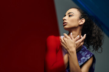 An athletic African American woman poses confidently against colorful glass panels, exuding strength and grace.