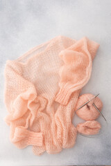 Home hobby, knitting a spider web sweater from pink threads, top view of the sweater and threads