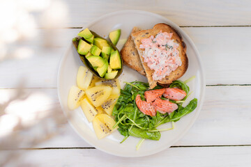 A healthy and delicious breakfast of avocado, toast, smoked salmon, and salad.
