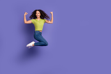 Full body photo of attractive teen woman jump winning dressed stylish green clothes isolated on purple color background
