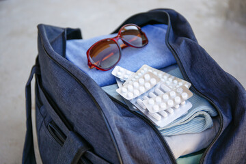 Clothes and pills in a travel bag. Concept of medication required in journey