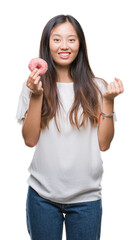 Young asian woman eating donut over isolated background screaming proud and celebrating victory and success very excited, cheering emotion