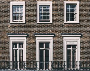 Obraz premium Three White Windows With Black Railings on Brick Building in London