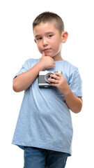 Dark haired little child holding vintage camera serious face thinking about question, very confused...