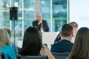 Diverse audience attentively listening to a keynote speaker at a business conference held in a...