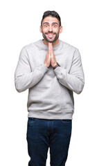 Young handsome man wearing sweatshirt over isolated background praying with hands together asking for forgiveness smiling confident.