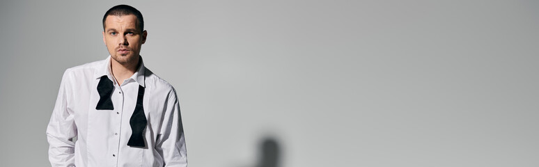 A stylish man poses with a double bowtie, wearing a white shirt against a white background.