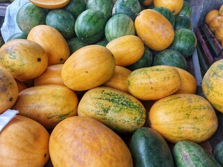 a pile of green skin and yellow skin watermelons fresh from the market