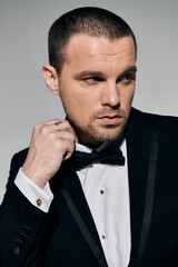 A man in a tuxedo adjusts his bow tie, looking sharp and confident.