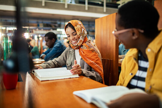 Happy students studying together in library