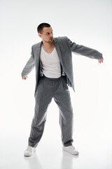 A stylish man in a gray suit and white sneakers strikes a pose.