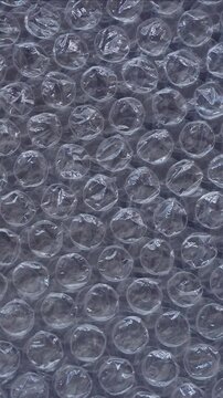 Rotating bubble wrap close-up. Top view plastic bubbles texture background. 4k vertical concept