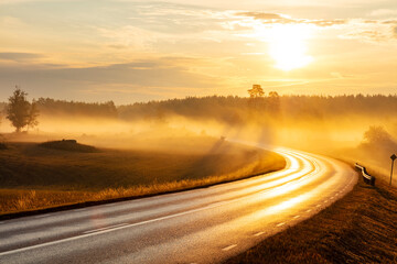 Curvy road amidst meadow against sky at sunset