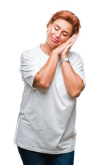 Atrractive senior caucasian redhead woman over isolated background sleeping tired dreaming and posing with hands together while smiling with closed eyes.