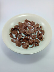Coco Crunch Cereal Drowned in Milk in a Small Cream Bowl on White Background: Enjoy a Delicious Breakfast Indulgence with Crunchy Cereal Submerged in Creamy Milk