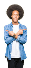 Young african american man with afro hair Pointing to both sides with fingers, different direction disagree