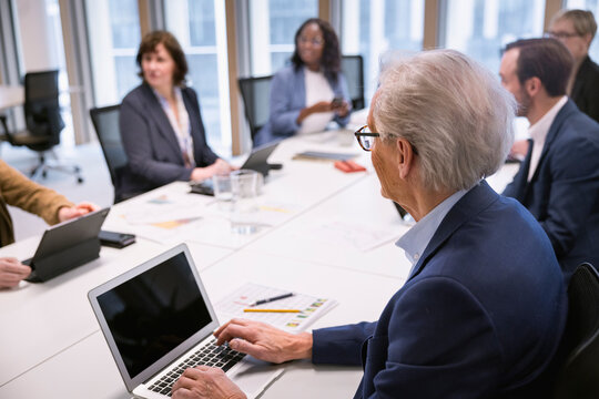 Senior businessman listening to colleagues during meeting in office