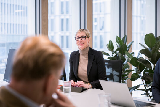 Mature businesswoman looking away while sitting at conference table in office