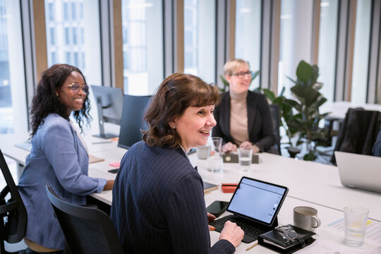 Smiling businesswomen looking away over conference table in office