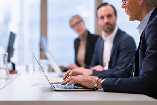 Midsection of senior businessman using laptop while working with colleagues in office