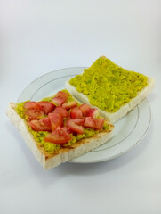Mashed Avocado and Diced Tomato on Toast: A delicious and nutritious breakfast choice featuring creamy mashed avocado and juicy diced tomato atop crispy toast on White Background