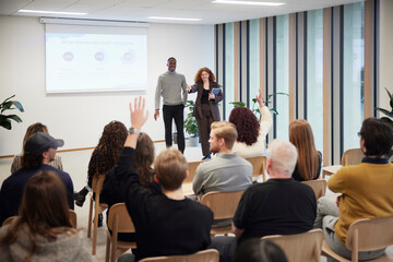 Audience communicating with coworkers during presentation in office