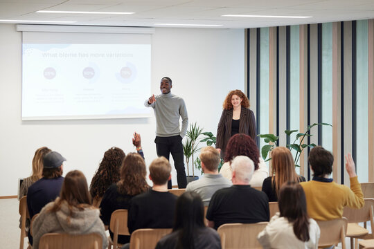 Multiracial colleagues giving presentation to employees in office