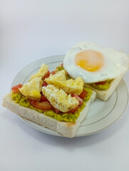 Mashed Avocado, Diced Tomato, Omelette, Sunny Side Up on Toast: Flavorful and Colorful Breakfast Combination Featuring Fresh Ingredients, Perfectly Presented on a Clean White Background